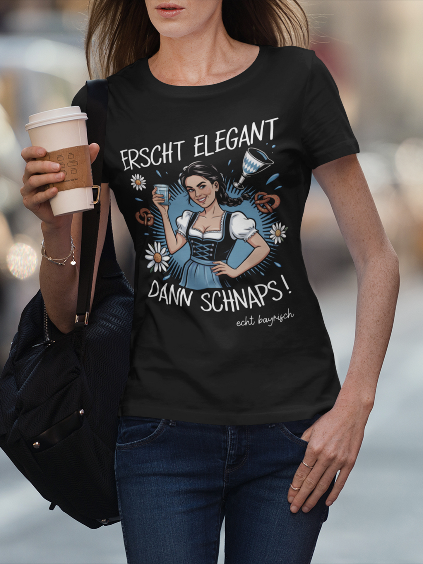 Junge Frau trägt schwarzes T-Shirt mit Dirndl-Motiv und Spruch „Erscht elegant dann Schnaps“, Oberkörperansicht