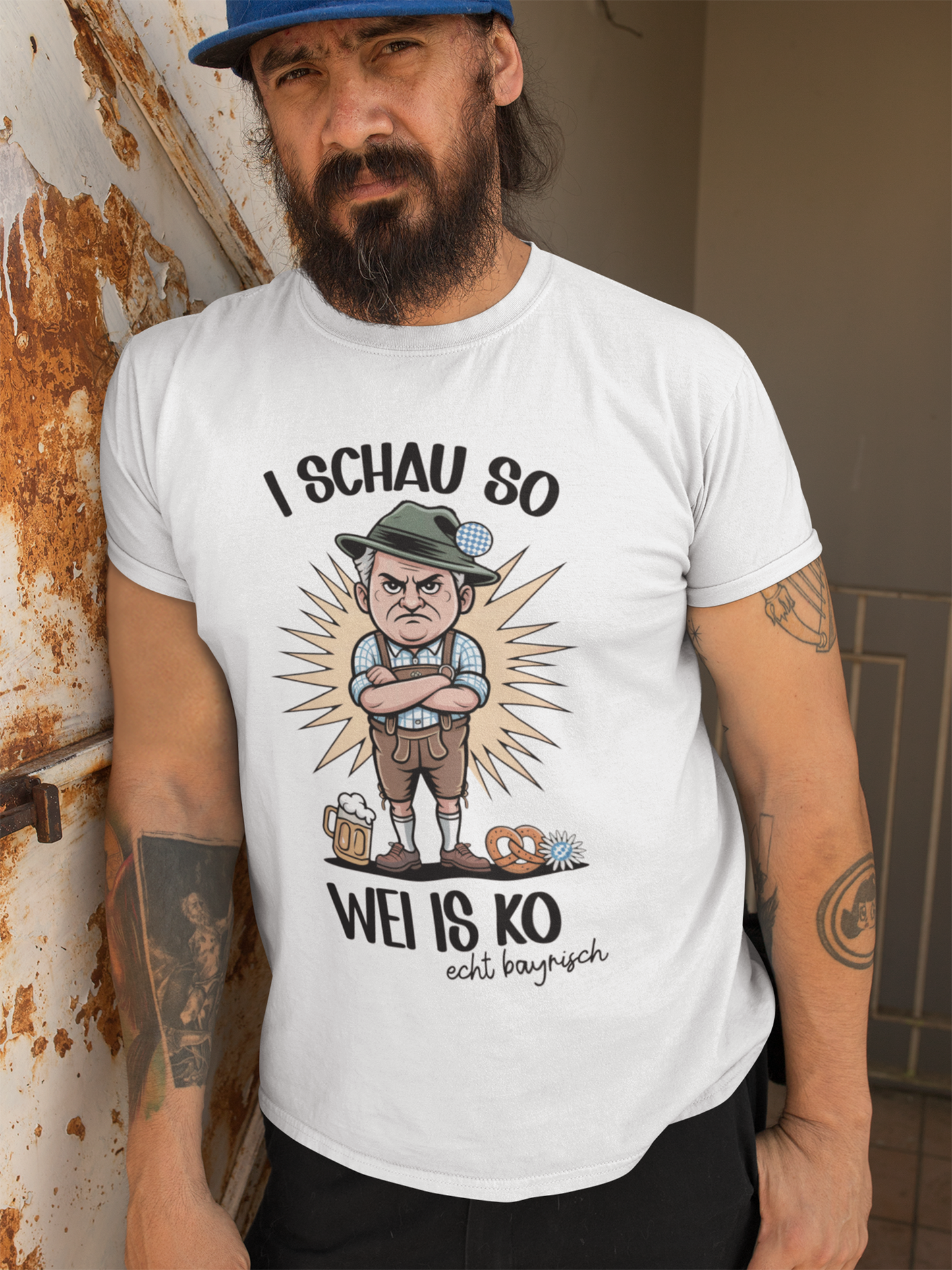 Mann mit Bart trägt weißes T-Shirt mit grimmigem Bayer-Motiv und Spruch „I schau so wei is ko“, Oberkörperansicht