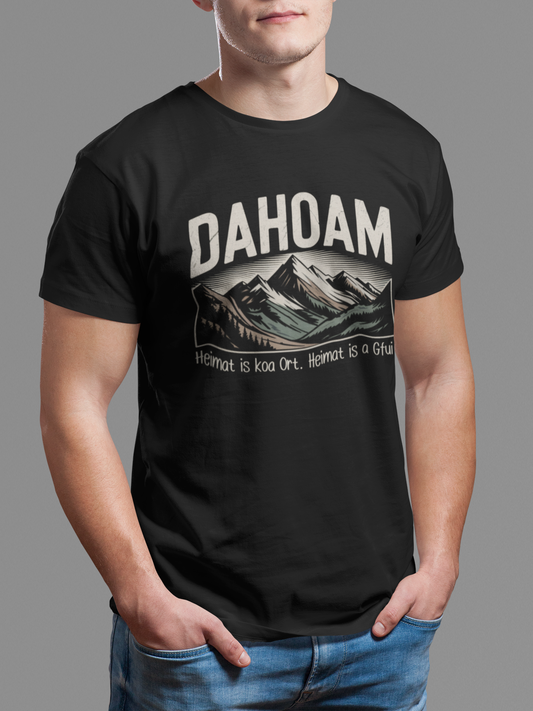 Junger Mann trägt schwarzes T-Shirt mit Sepia-Bergmotiv und Heimat-Spruch, Oberkörperansicht