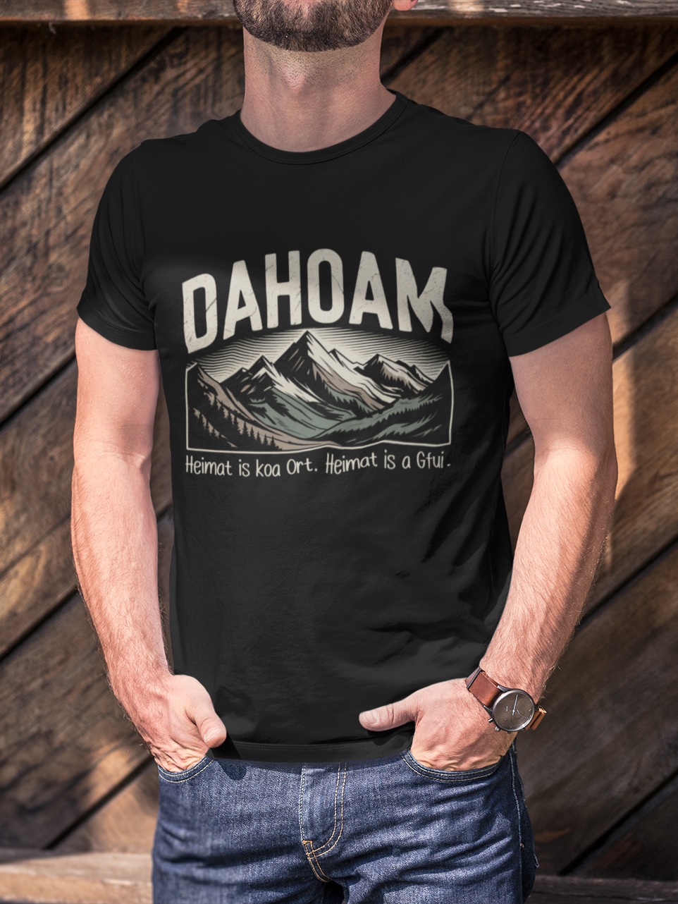 Junger Mann trägt schwarzes T-Shirt mit Sepia-Bergmotiv und Heimat-Spruch, Oberkörperansicht