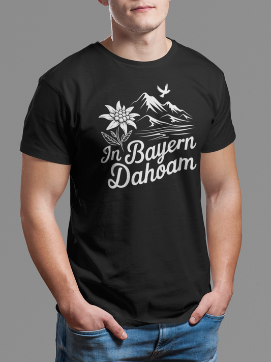 Junger Mann trägt schwarzes T-Shirt mit Bergpanorama und „In Bayern dahoam“-Schriftzug, Oberkörperansicht