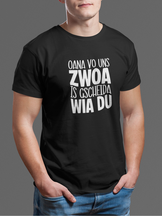 Junger Mann trägt schwarzes T-Shirt mit weißem Text „Oana vo uns Zwoa is gscheida wia du“, Oberkörperansicht