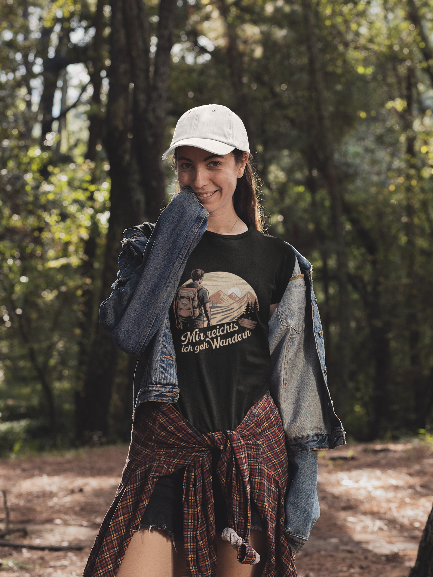 Junge Frau im Wald, sie trägt schwarzes T-Shirt mit Bergmotiv und Text „Mir reicht’s, ich geh wandern“, Oberkörperansicht