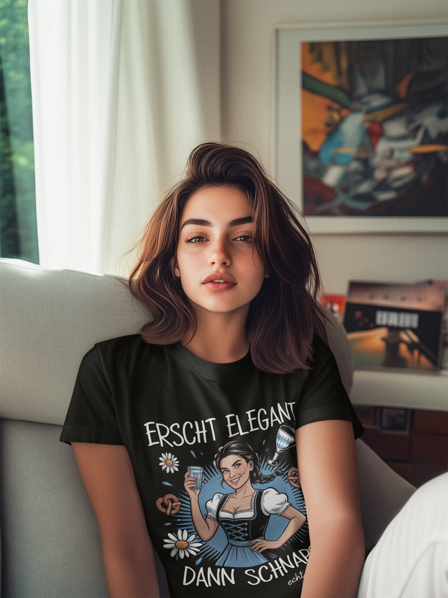 Junge Frau trägt schwarzes T-Shirt mit Dirndl-Motiv und Spruch „Erscht elegant dann Schnaps“, Oberkörperansicht