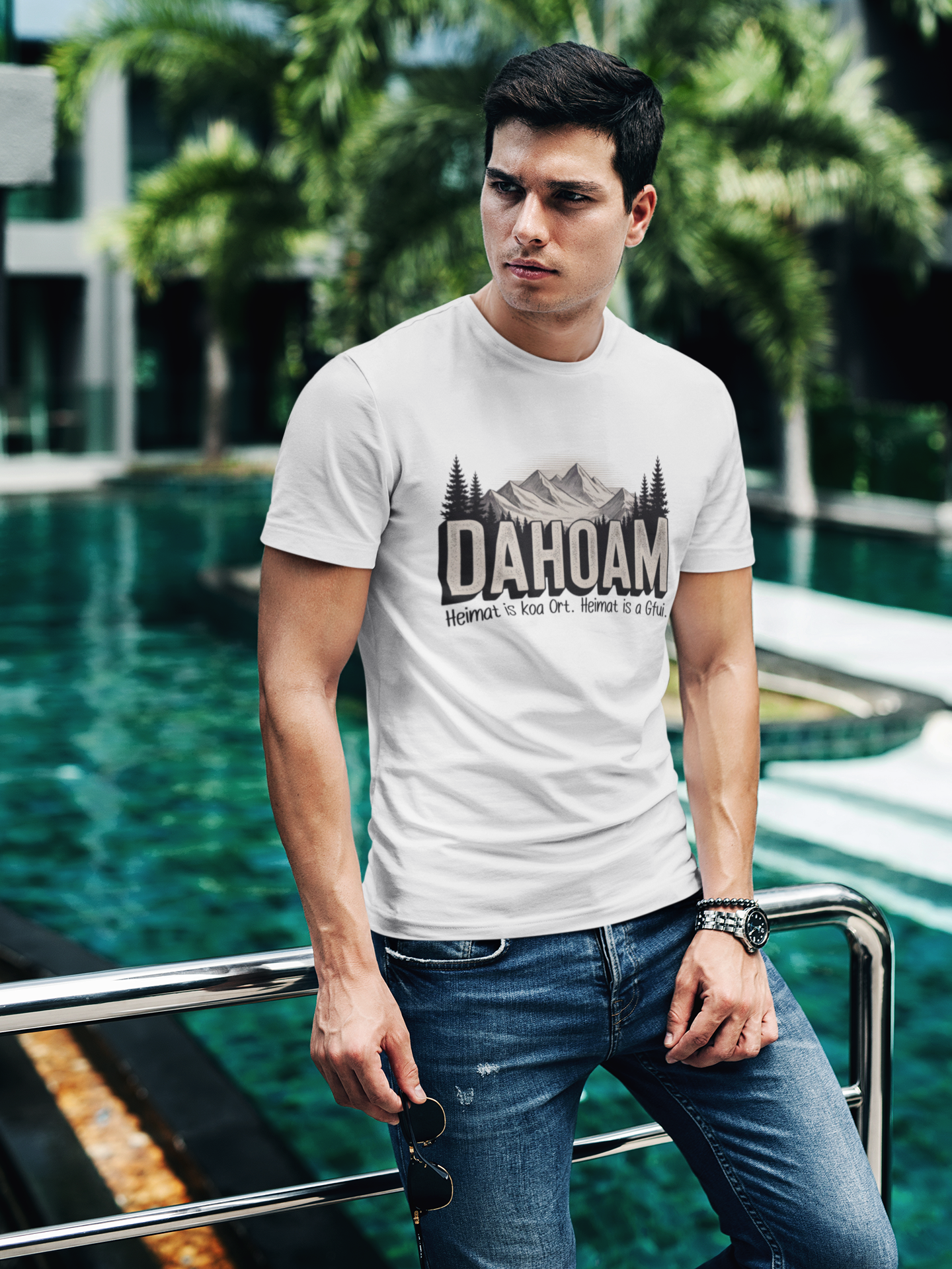 Junger Mann trägt weißes T-Shirt mit Sepia-Bergmotiv und großem „Dahoam“-Schriftzug, Oberkörperansicht