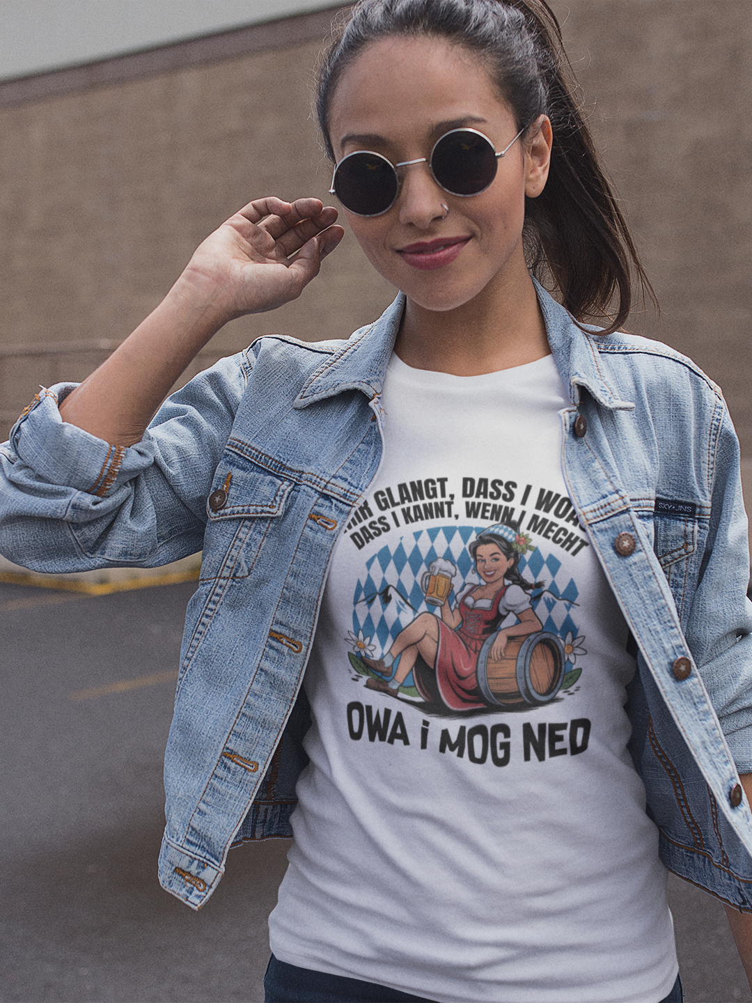 Junge Frau trägt weißes T-Shirt mit Motiv „Owa i mog ned“ und bayrischem Madl, Oberkörperansicht