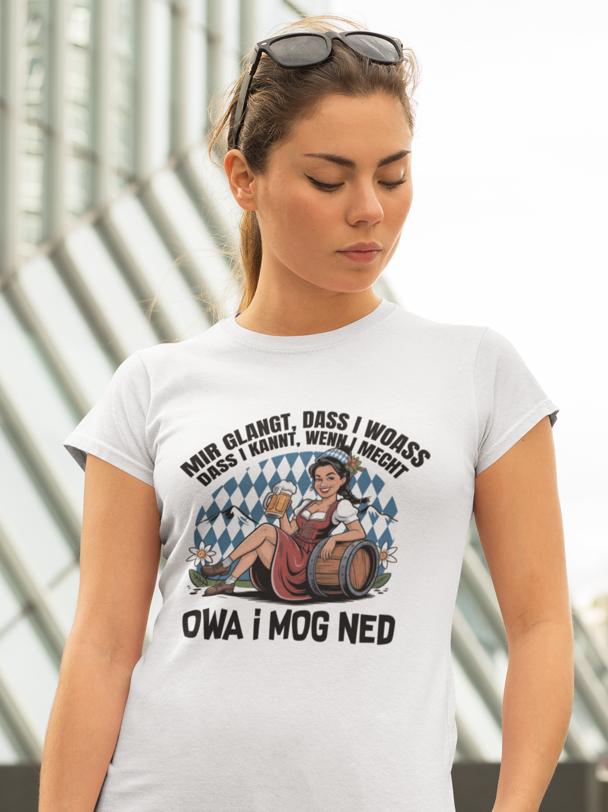 Junge Frau trägt weißes T-Shirt mit Motiv „Owa i mog ned“ und bayrischem Madl, Oberkörperansicht