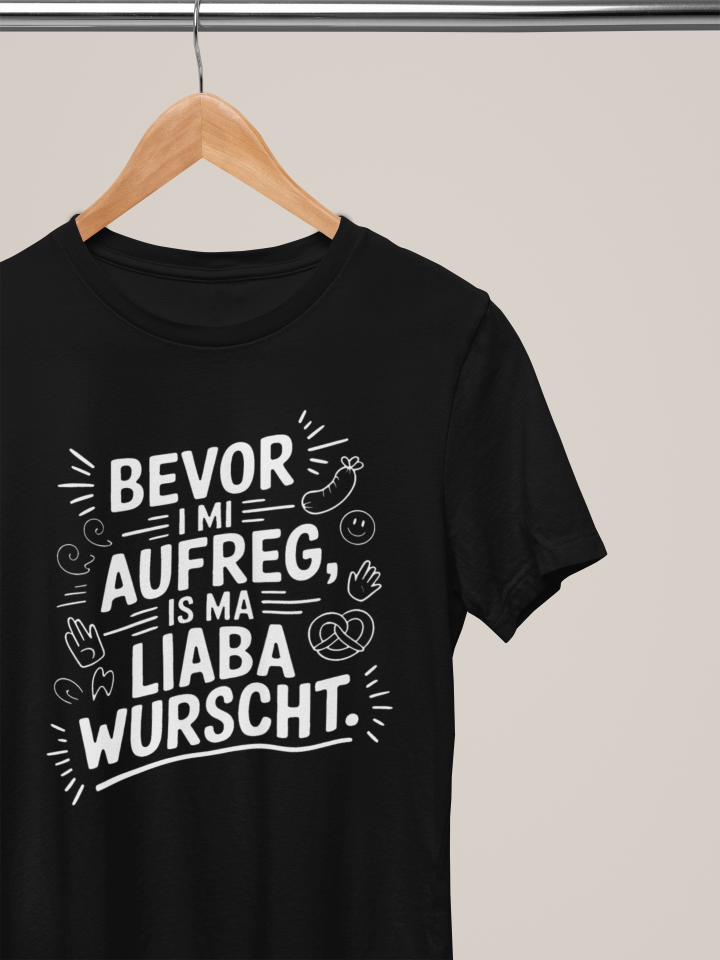 Schwarzes T-Shirt mit weißem Text „Bevor I mi aufreg, is ma liaba wurscht“ auf Kleiderbügel 