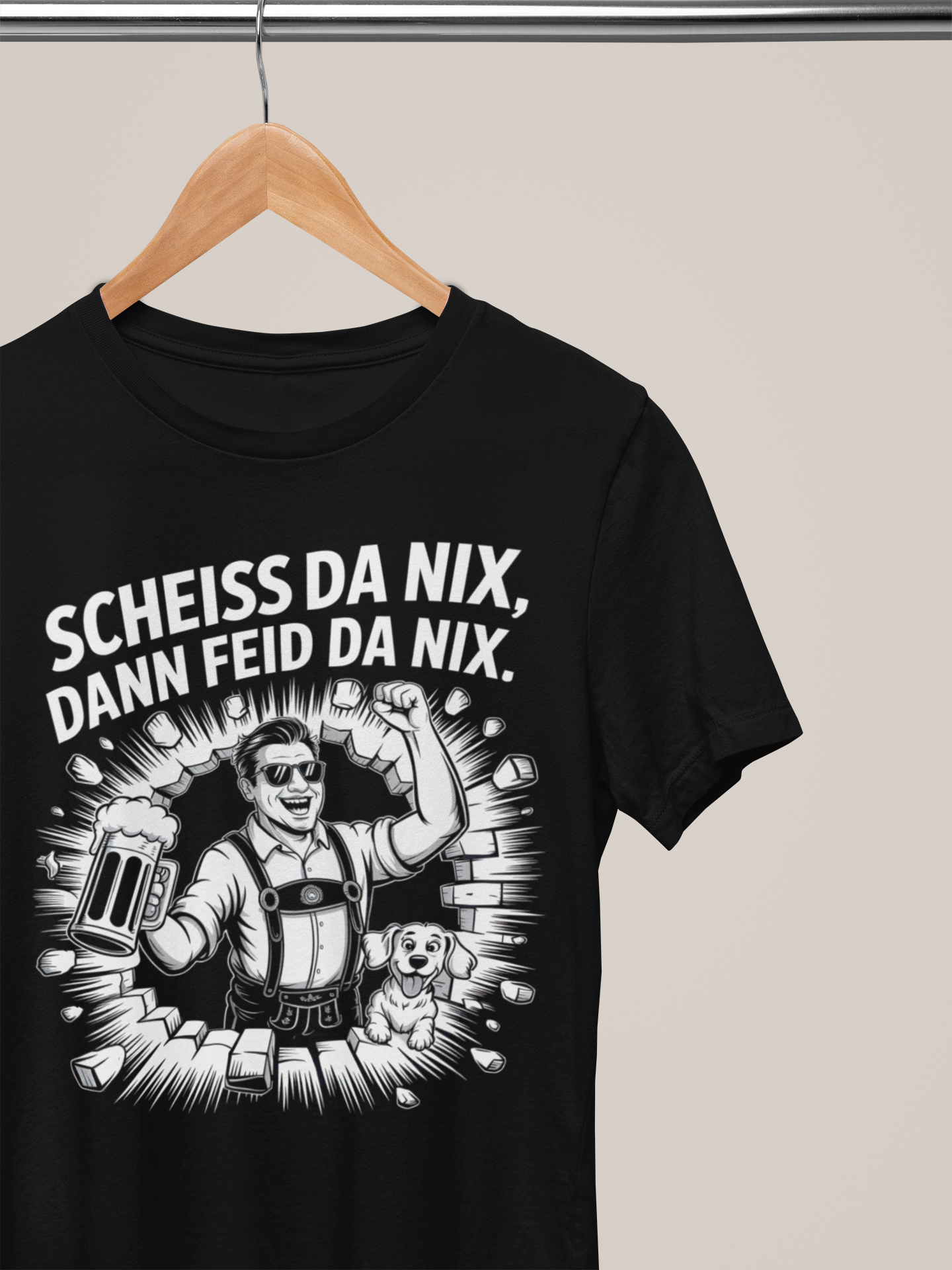 Schwarzes T-Shirt auf Kleiderbügel, mit weißem Text „Scheiß da nix, dann feid da nix“ und Comic-Motiv eines Bayern mit Hund und Wand.
