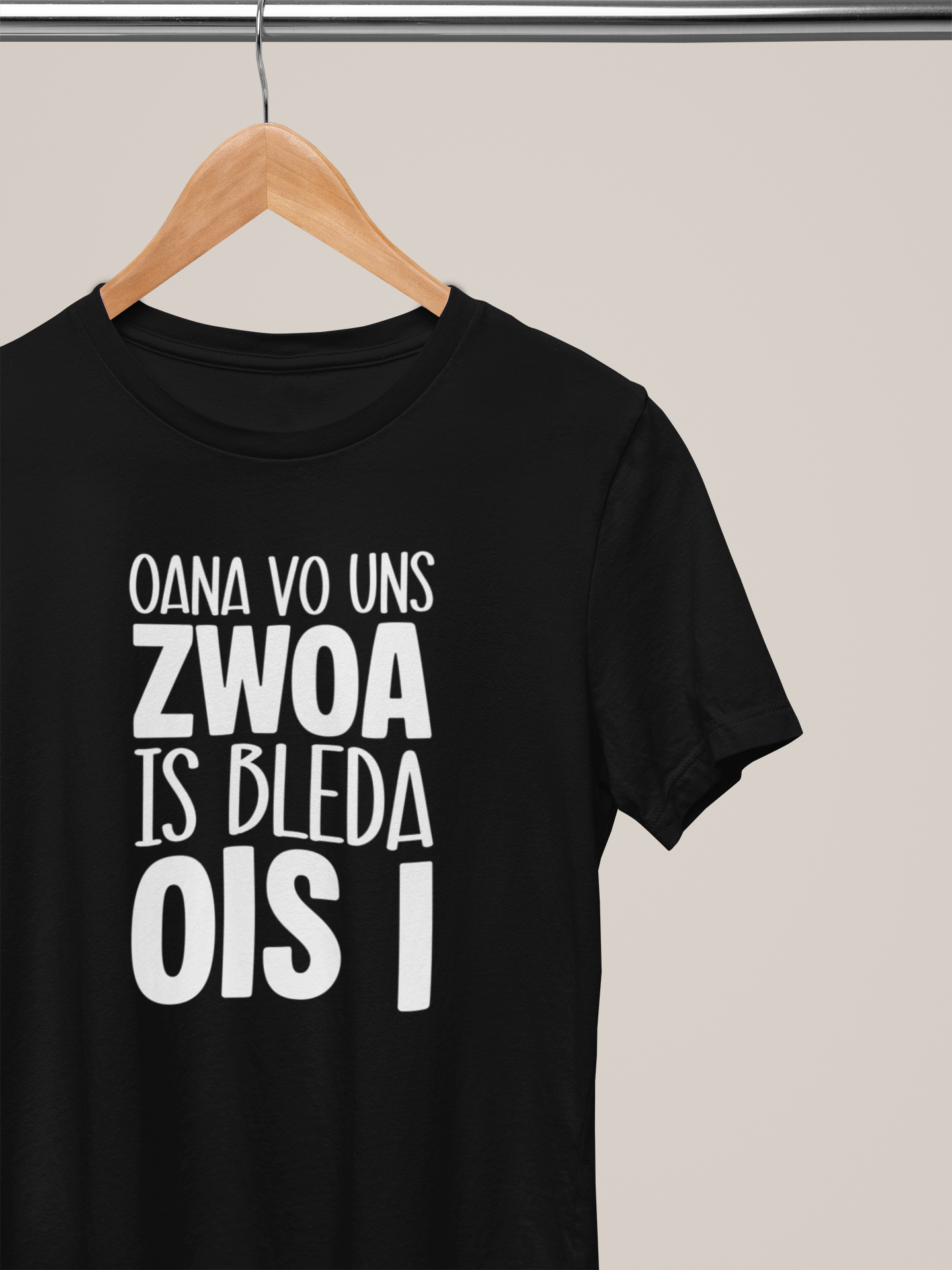 Schwarzes T-Shirt mit weißem Text „Oana vo uns Zwoa is bleda ois i“, auf Kleiderbügel an Stange