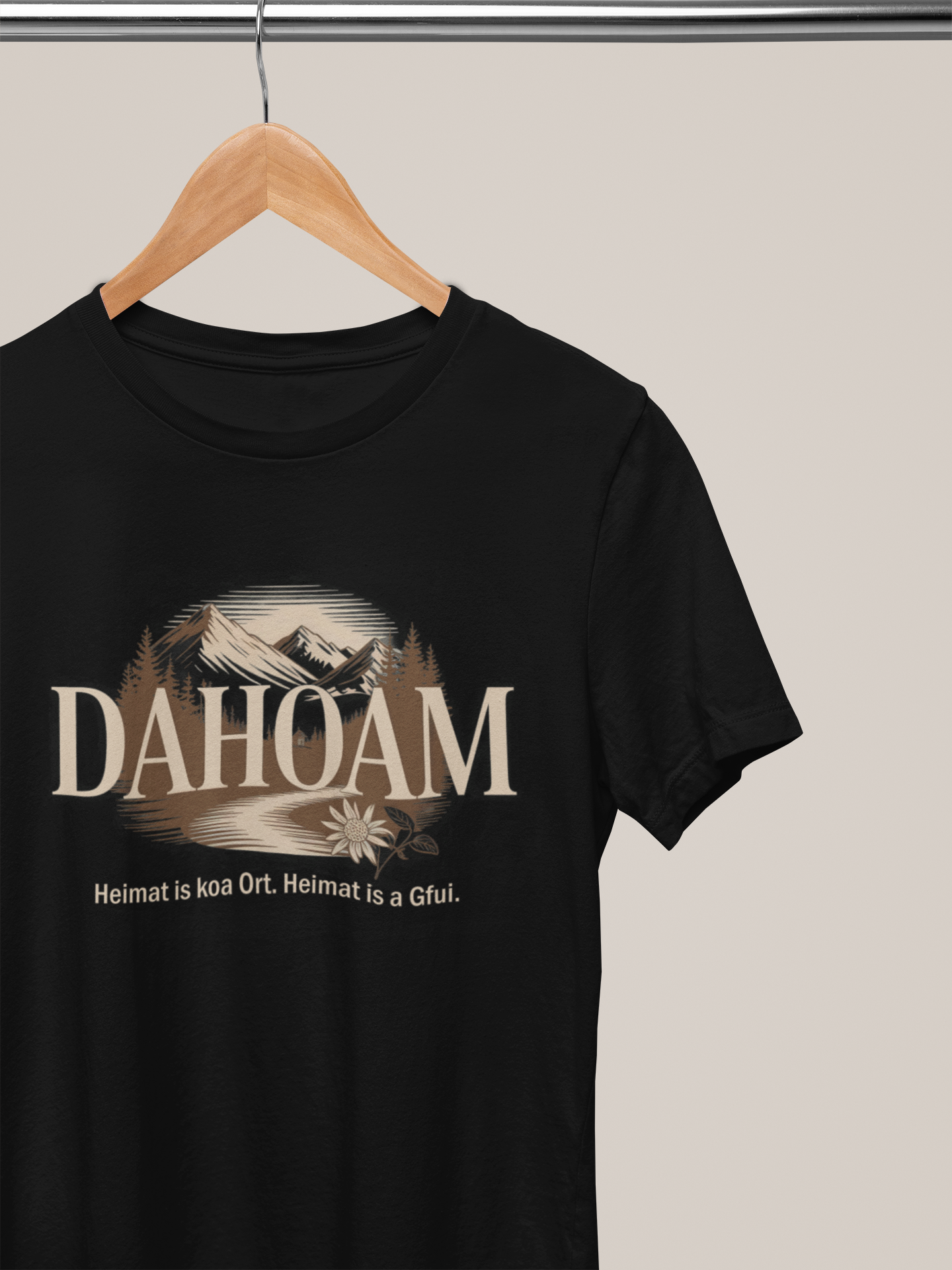 Schwarzes T-Shirt mit Bergmotiv in Sepia und dem Text „Dahoam. Heimat is koa Ort. Heimat is a Gfui.“, auf Kleiderbügel