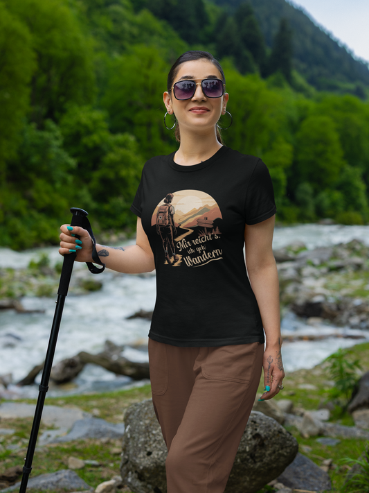 Frau mit Wanderstock und brauner Hose, sie trägt schwarzes T-Shirt mit elegantem Wandermotiv (Oberkörper). Im Hintergrund ein Fluss und Wald.