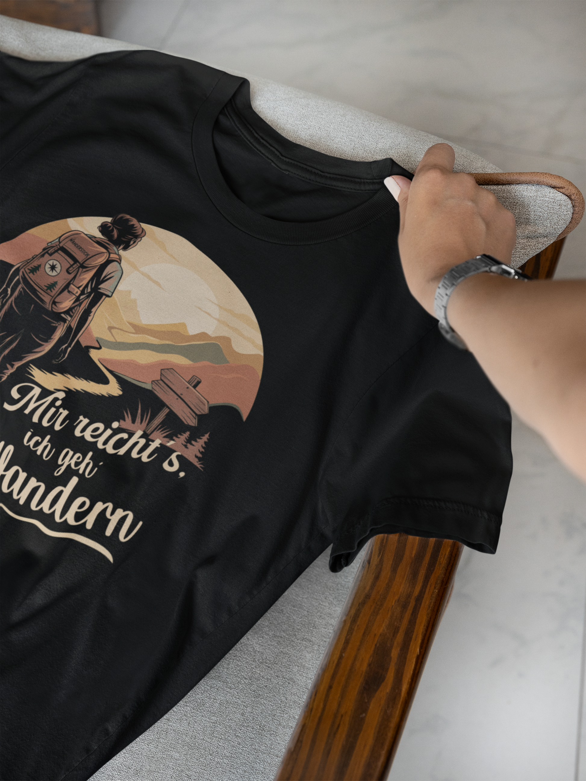 Schwarzes T-Shirt, liegend, mit Hand, mit Wandermotiv in Sepia-Tönen und Spruch „Mir reicht’s, ich geh wandern“